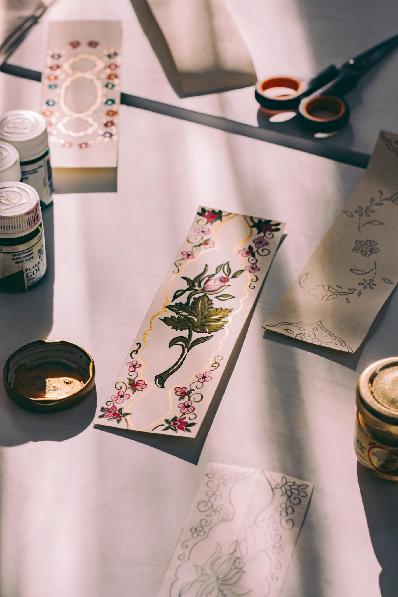 Art supplies and floral designs on a sunlit table, perfect for creative projects.