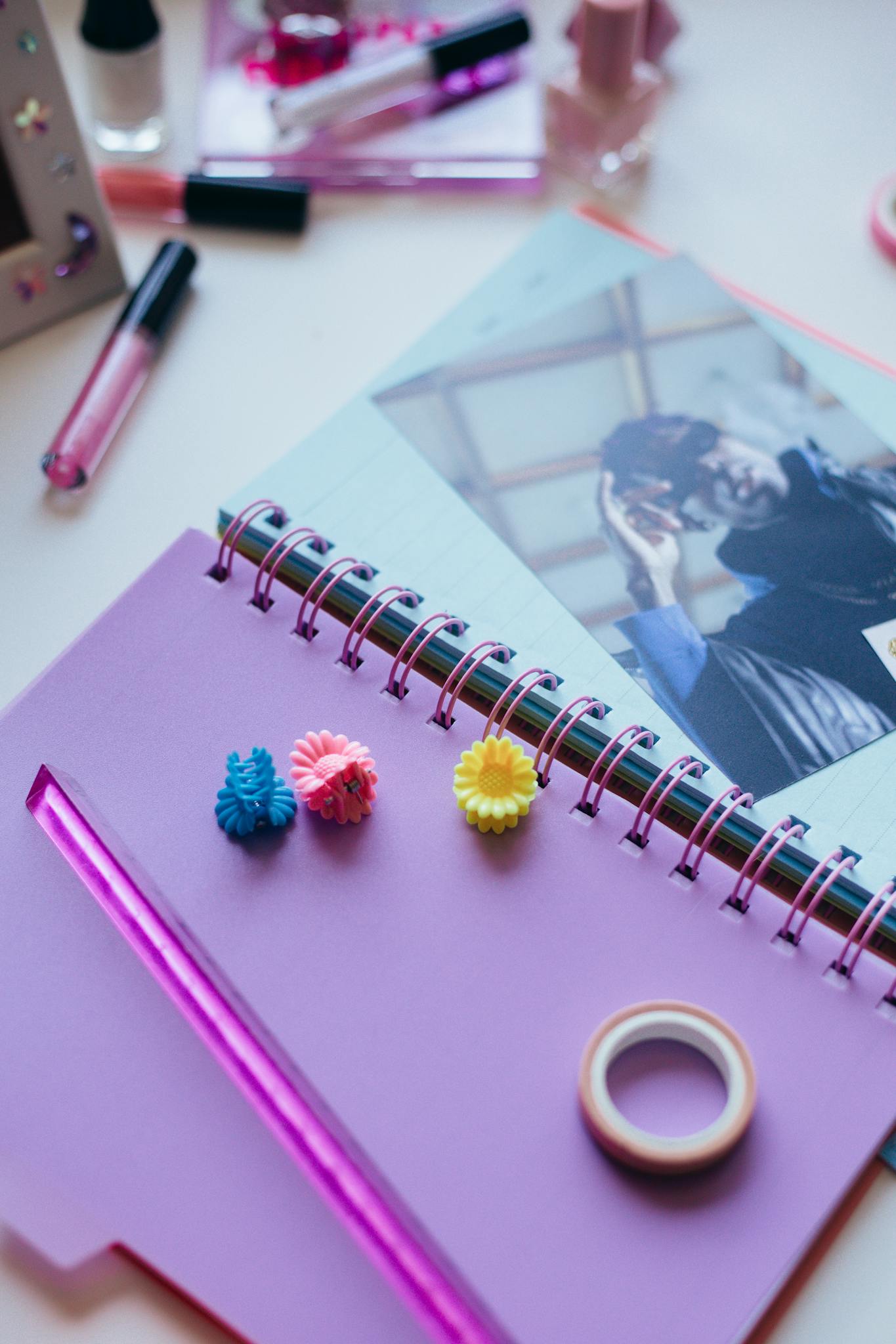 Colorful arts and crafts materials on a desk featuring a spiral notebook and photo album.
