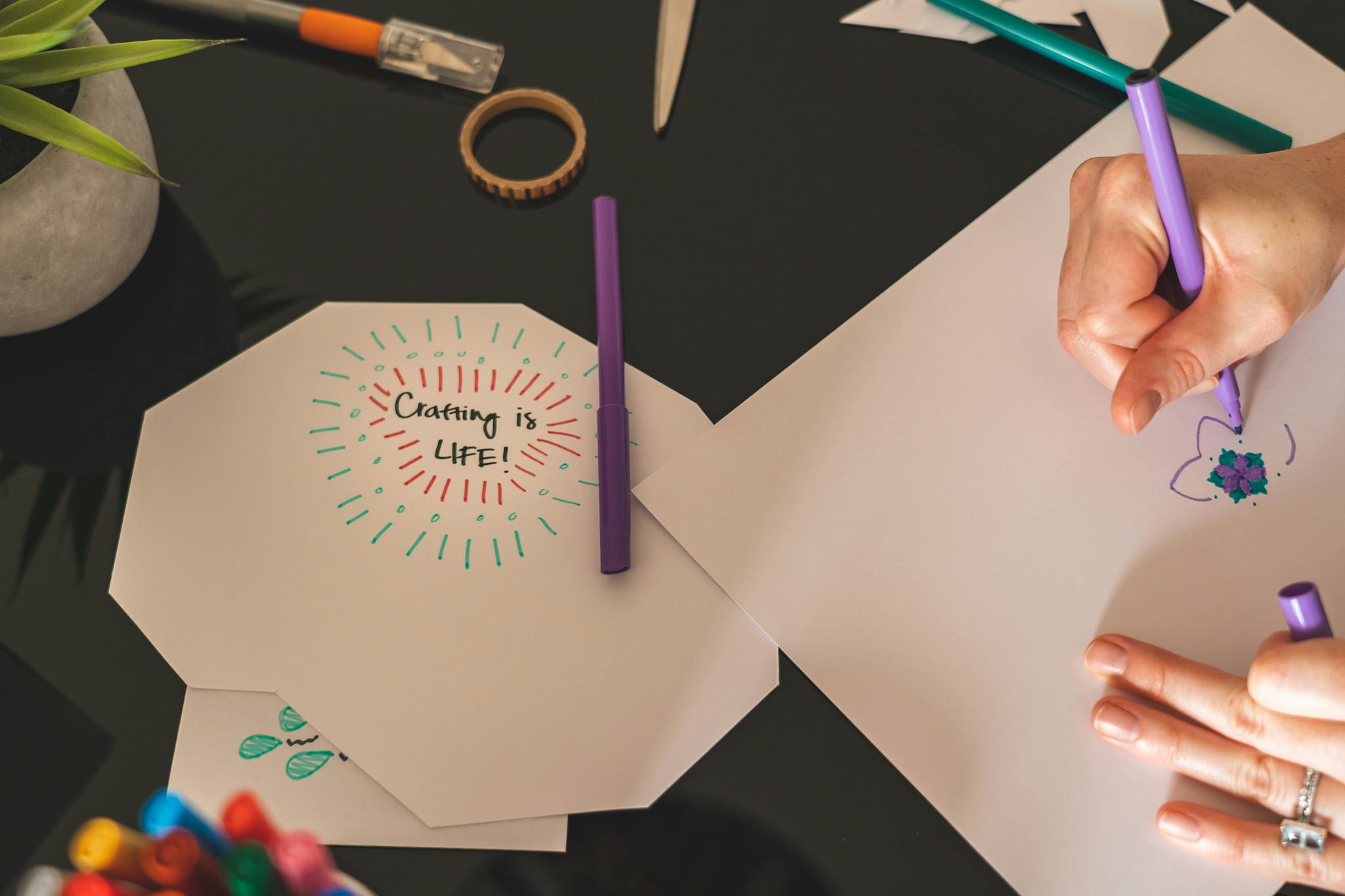 Hands creating art with markers on paper. Emphasizes creativity and artsy crafts.